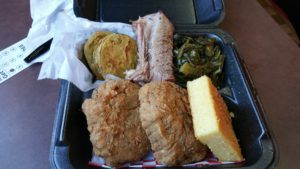 Salmon croquette with fried green tomatoes, a slice of beef brisket, collard greens and cornbread.